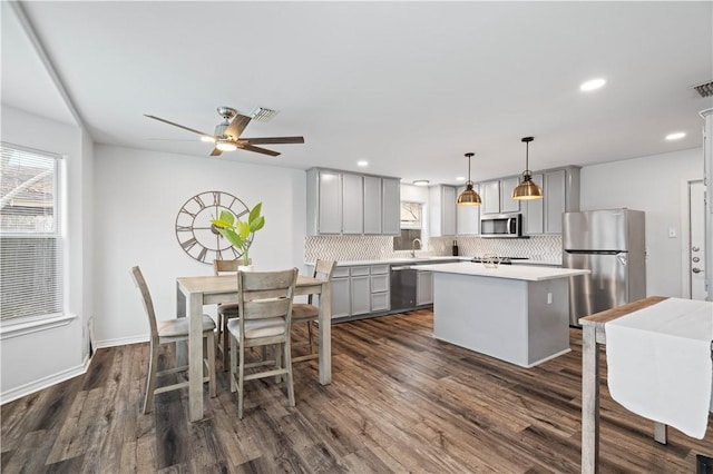 kitchen with stainless steel appliances, hanging light fixtures, light countertops, gray cabinets, and a center island