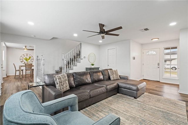 living area featuring stairs, a ceiling fan, wood finished floors, and recessed lighting