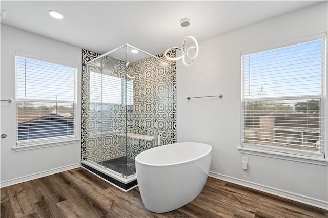 full bathroom featuring a soaking tub, baseboards, wood finished floors, and a stall shower