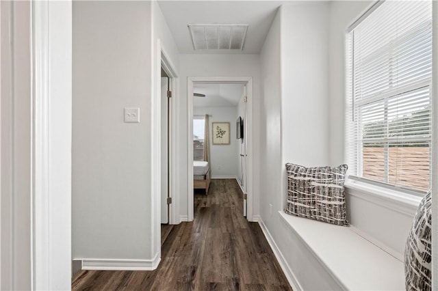 hall with dark wood-style flooring, visible vents, and baseboards