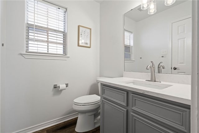 bathroom with wood finished floors, vanity, toilet, and baseboards