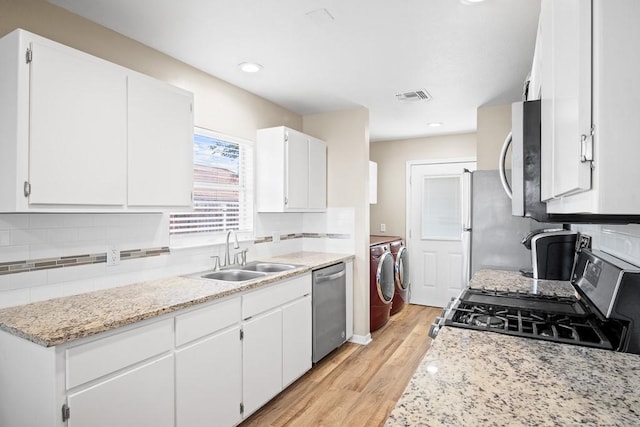 906 S Young St, Rockport, TX 78382 - kitchen with visible vents, decorative backsplash, stainless steel appliances, washer and dryer, and a sink