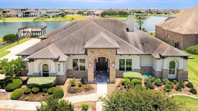 5716 S Oso Pkwy, Corpus Christi, TX 78414 - view of front facade with stone siding, stucco siding, a shingled roof, a water view, and a residential view