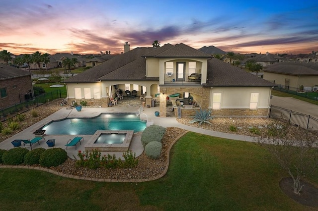 5716 S Oso Pkwy, Corpus Christi, TX 78414 - back of property at dusk with a balcony, stone siding, stucco siding, a patio area, and a pool with connected hot tub