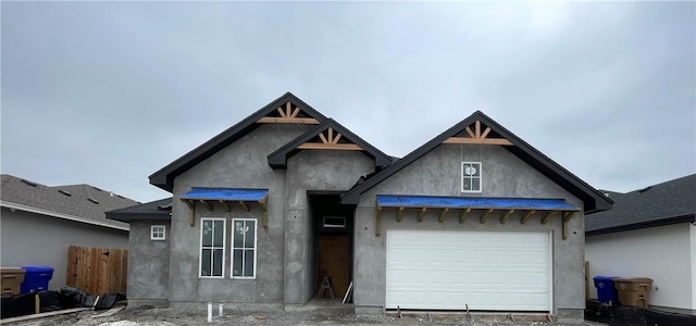 view of front facade featuring a garage, fence, and stucco siding