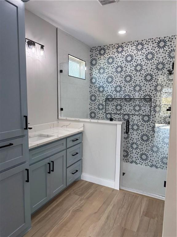 bathroom with a stall shower, wood finished floors, and vanity