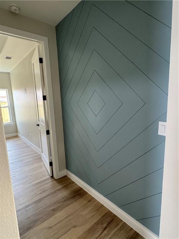 hallway featuring visible vents, baseboards, and wood finished floors