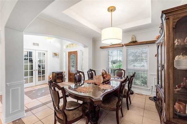 tiled dining space featuring french doors, crown molding, and a raised ceiling