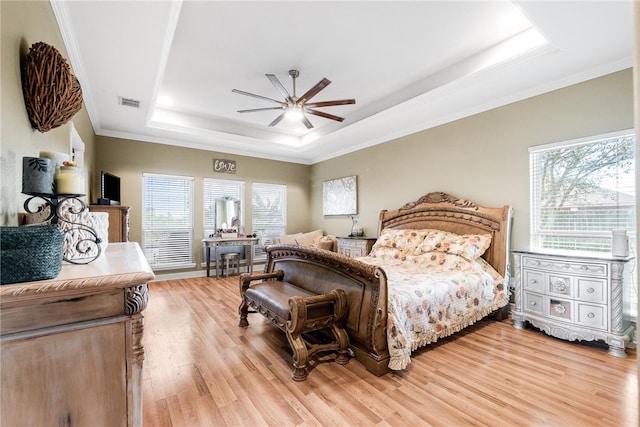 bedroom with ceiling fan, multiple windows, light hardwood / wood-style floors, and a raised ceiling