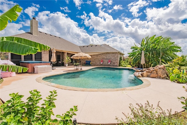 view of swimming pool featuring a hot tub and a patio area