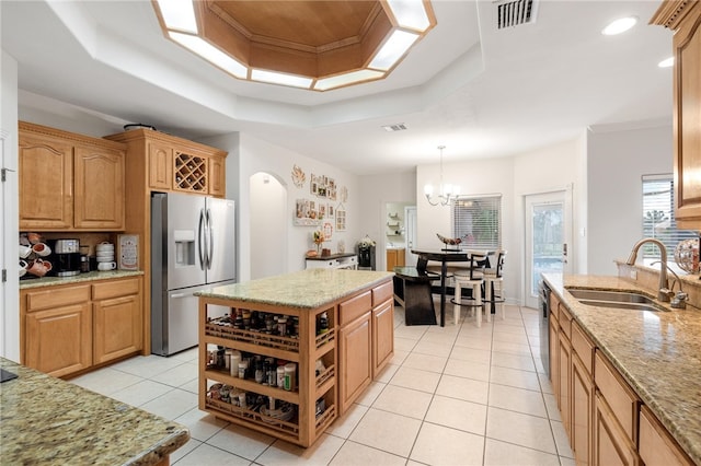 kitchen with stainless steel appliances, sink, light tile patterned floors, a raised ceiling, and decorative light fixtures