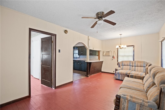 unfurnished living room featuring dark hardwood / wood-style floors, a textured ceiling, an AC wall unit, and ceiling fan with notable chandelier