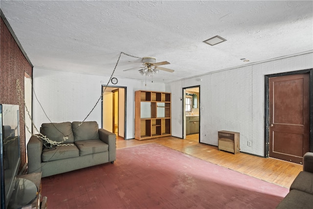 living room with hardwood / wood-style flooring, ceiling fan, and a textured ceiling