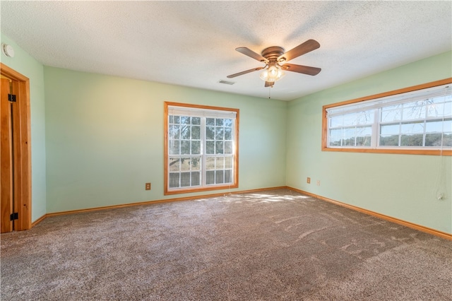 carpeted empty room featuring ceiling fan, a healthy amount of sunlight, and a textured ceiling