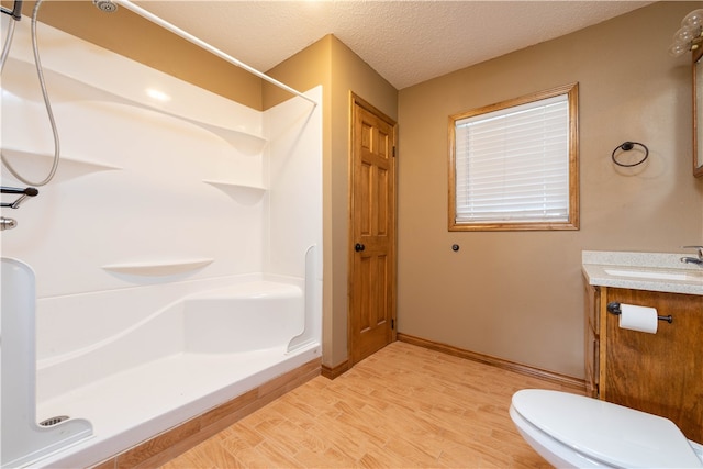 bathroom featuring toilet, a textured ceiling, hardwood / wood-style flooring, vanity, and walk in shower