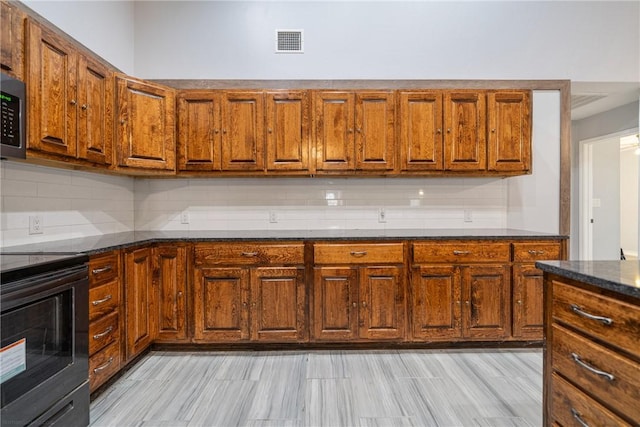 kitchen featuring tasteful backsplash, black electric range oven, and dark stone countertops