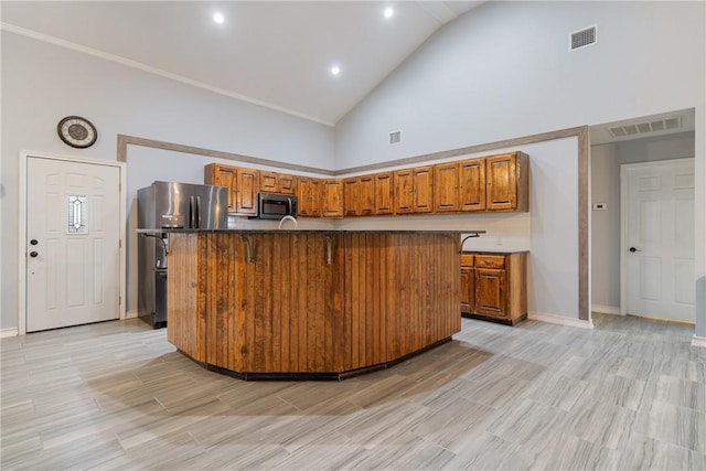 kitchen featuring a center island with sink, high vaulted ceiling, a breakfast bar, and appliances with stainless steel finishes