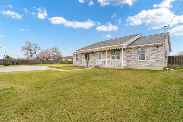 rear view of house featuring a lawn and covered porch