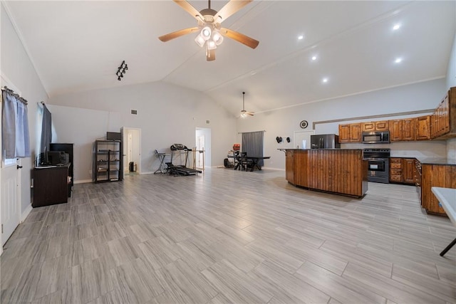 interior space with ceiling fan, a kitchen island, appliances with stainless steel finishes, and vaulted ceiling