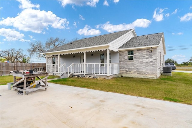 rear view of house featuring covered porch, a yard, and a patio