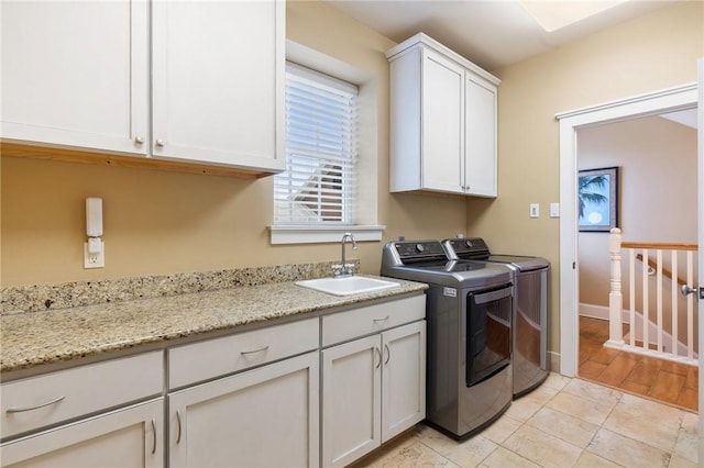 clothes washing area featuring light tile patterned floors, sink, washing machine and clothes dryer, and cabinets