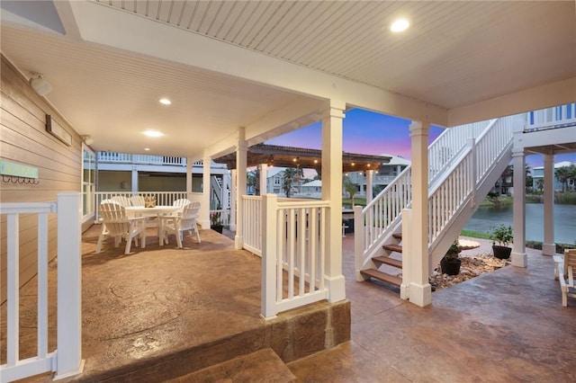 patio terrace at dusk featuring a water view