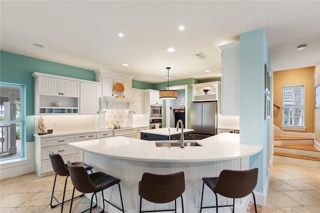 kitchen with appliances with stainless steel finishes, white cabinetry, hanging light fixtures, and sink