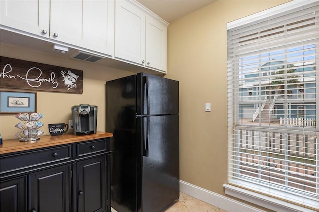 kitchen featuring black fridge, butcher block counters, and white cabinets