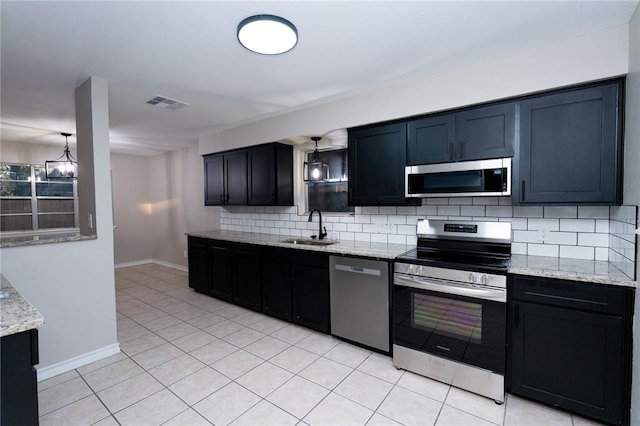 kitchen featuring light stone countertops, sink, stainless steel appliances, tasteful backsplash, and a chandelier