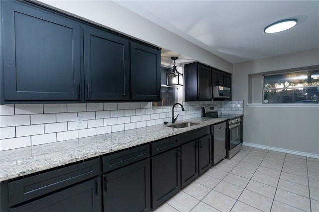 kitchen with backsplash, light stone counters, stainless steel appliances, sink, and light tile patterned floors