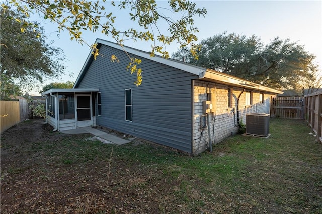 back of house featuring central AC unit, a sunroom, and a yard