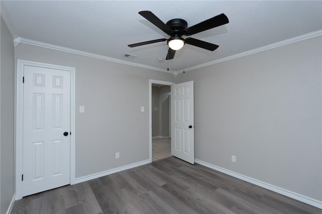 unfurnished bedroom with ceiling fan, dark wood-type flooring, and ornamental molding