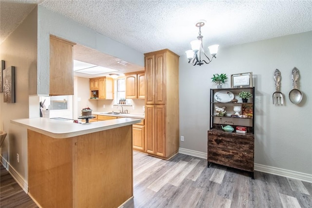 7322 Milky Way Dr, Corpus Christi, TX 78412 - kitchen featuring light wood-style flooring, a chandelier, light countertops, a peninsula, and a textured ceiling