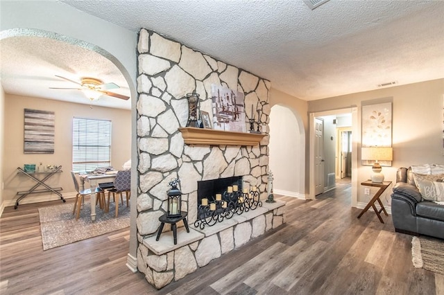 7322 Milky Way Dr, Corpus Christi, TX 78412 - living room featuring arched walkways, a textured ceiling, ceiling fan, wood finished floors, and a fireplace