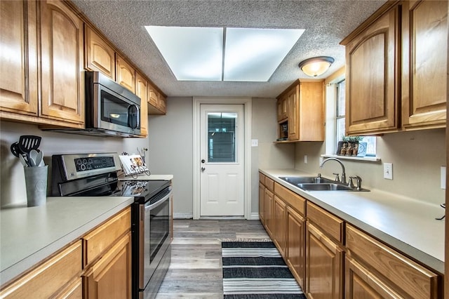 7322 Milky Way Dr, Corpus Christi, TX 78412 - kitchen featuring stainless steel appliances, a textured ceiling, light countertops, light wood-style flooring, and brown cabinetry