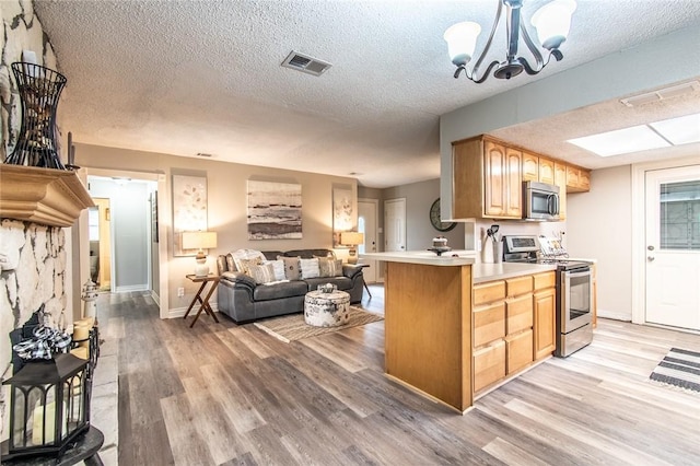 7322 Milky Way Dr, Corpus Christi, TX 78412 - kitchen with appliances with stainless steel finishes, light countertops, open floor plan, light wood-style floors, and a textured ceiling