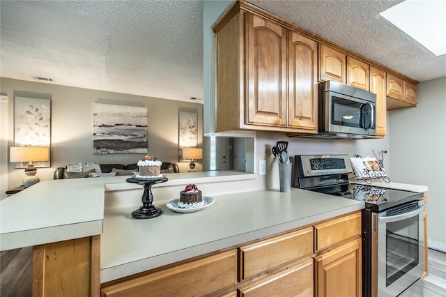 7322 Milky Way Dr, Corpus Christi, TX 78412 - kitchen featuring stainless steel appliances, a textured ceiling, light countertops, open floor plan, and light wood-type flooring