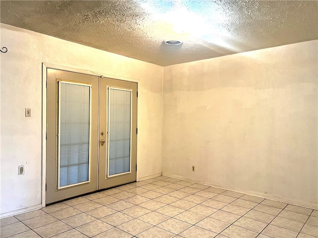 unfurnished room with a textured ceiling, light tile patterned floors, and french doors