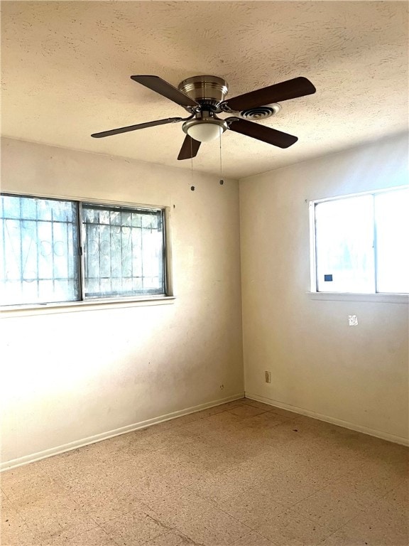 spare room with ceiling fan, a textured ceiling, and a healthy amount of sunlight