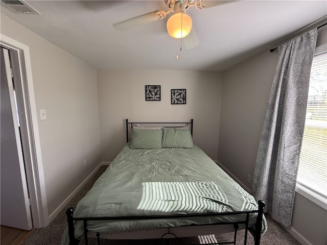 bedroom with ceiling fan, carpet floors, and a textured ceiling