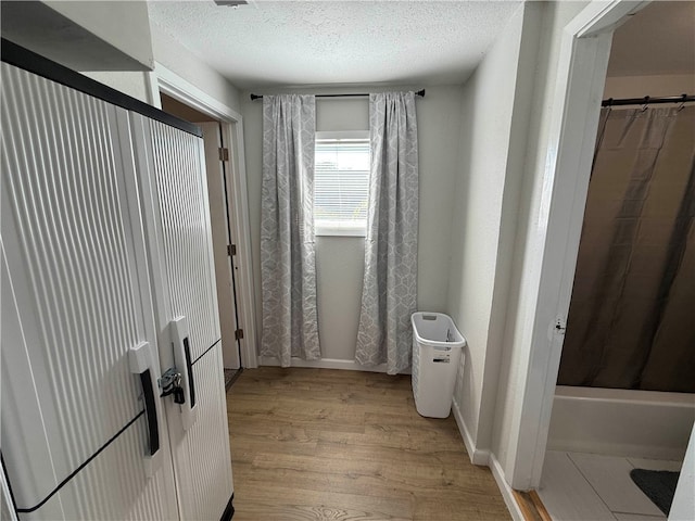 bathroom with wood-type flooring, a textured ceiling, and shower / bath combo with shower curtain