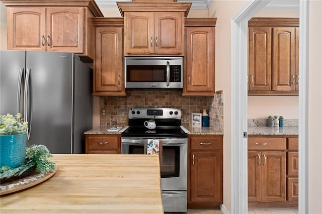 kitchen featuring crown molding, stainless steel appliances, backsplash, light tile patterned floors, and wood counters