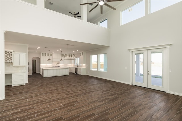 unfurnished living room with a wealth of natural light, dark hardwood / wood-style floors, and a towering ceiling