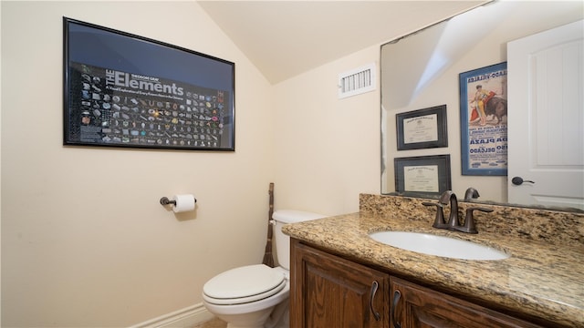 bathroom featuring lofted ceiling, toilet, and vanity