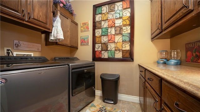 clothes washing area with cabinets, independent washer and dryer, and light tile patterned floors