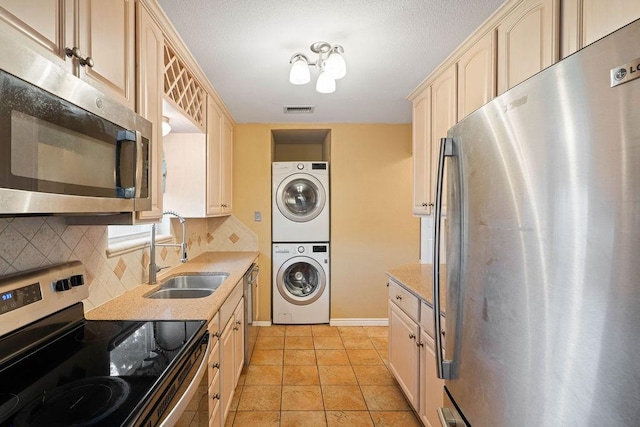 3605 Rushing Blvd, Corpus Christi, TX 78410 - kitchen featuring appliances with stainless steel finishes, a sink, stacked washer / drying machine, tasteful backsplash, and light countertops