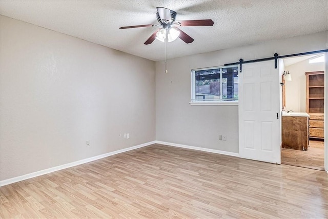 10502 Hemlock Rd, Corpus Christi, TX 78410 - unfurnished bedroom featuring light wood finished floors, a barn door, a textured ceiling, and ceiling fan