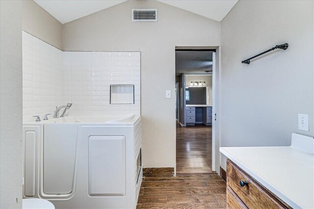 10502 Hemlock Rd, Corpus Christi, TX 78410 - full bath featuring wood finished floors, a garden tub, washer / dryer, vaulted ceiling, and vanity