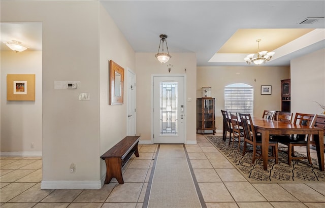 entrance foyer featuring an inviting chandelier, a raised ceiling, light tile patterned floors, and visible vents