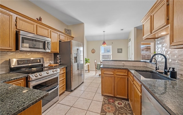 kitchen featuring a sink, stainless steel appliances, dark stone counters, light tile patterned floors, and decorative backsplash